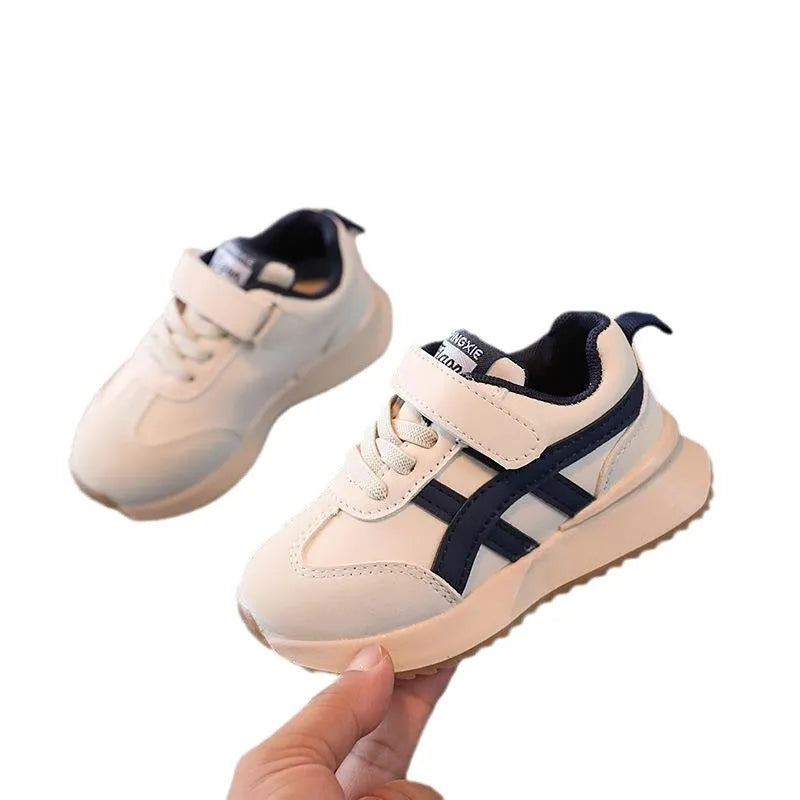 A pair of children's casual sneakers with a Velcro strap, shown in a neutral solid colour.