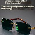 Frameless sunglasses with dark green crystal lenses showing a decorative wealth attracting pattern.