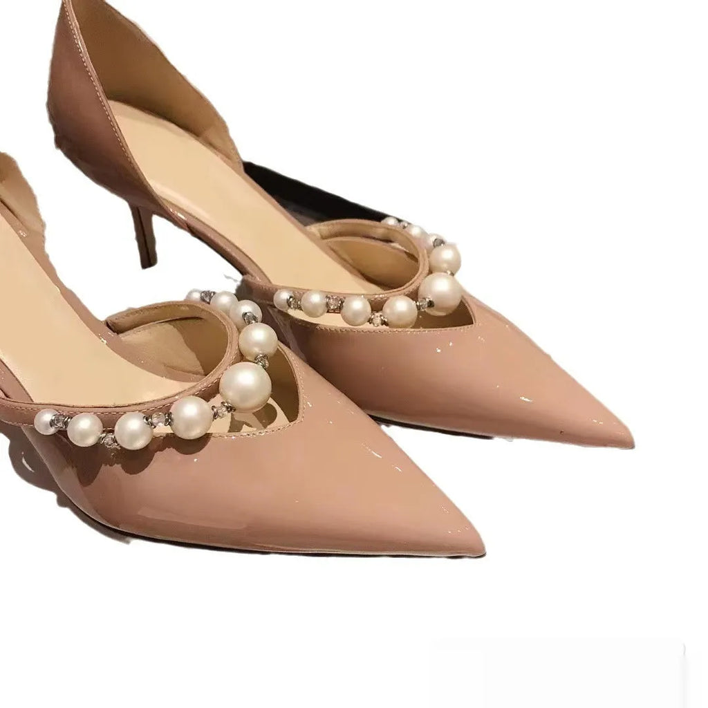 Women's black pointed toe stiletto high heels with pearl detail on patent leather-look upper.