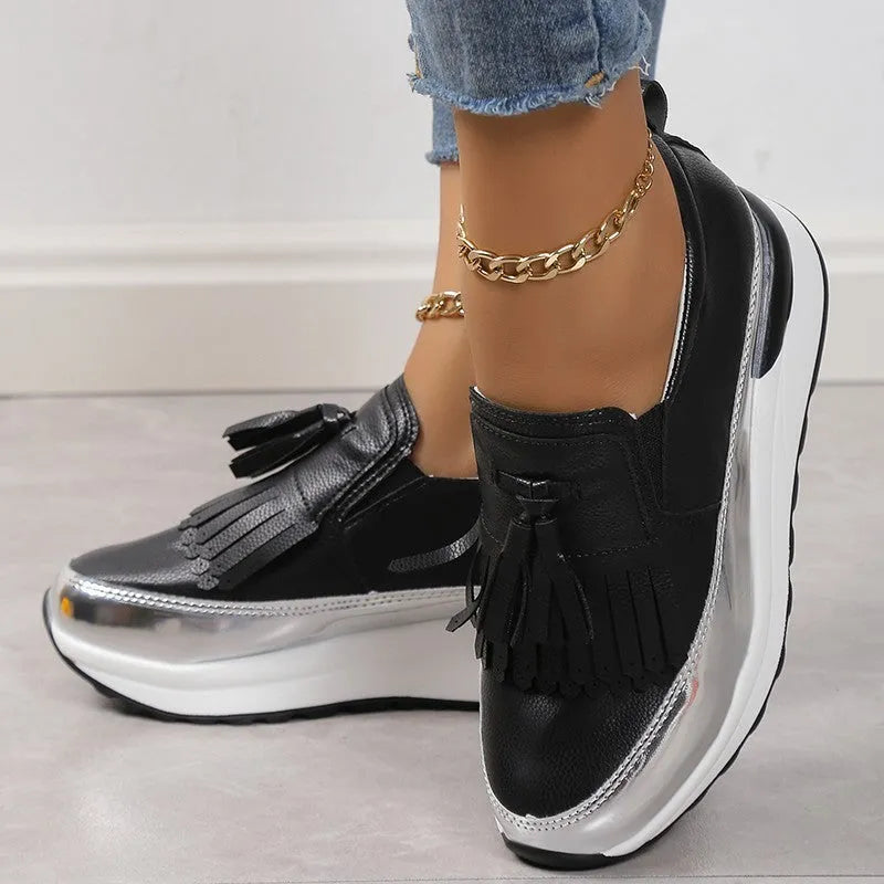 Women's black casual platform shoes with a muffin wedge heel and a decorative tassel.