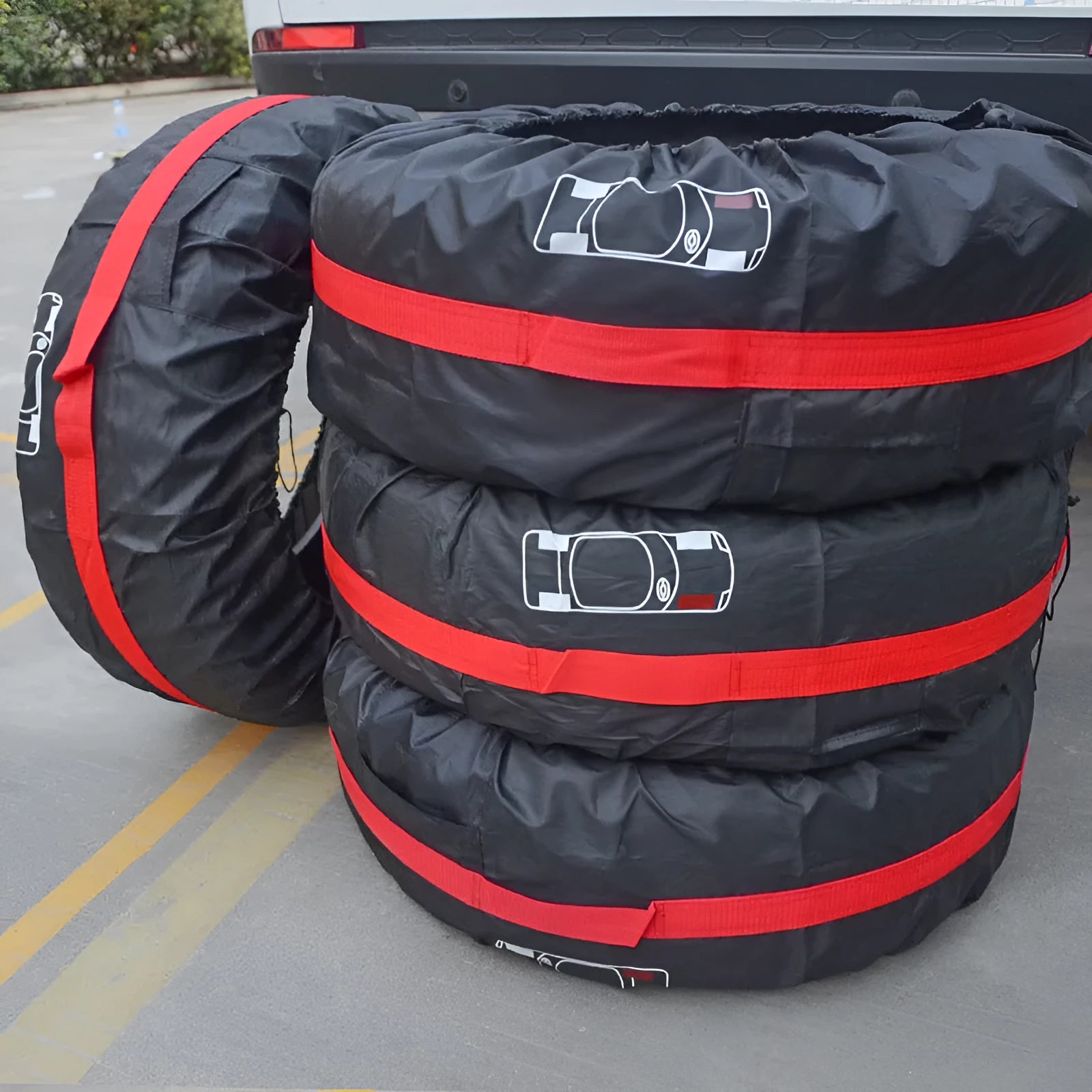 Set of four black Oxford cloth tyre protective covers with red belt closures laid flat.