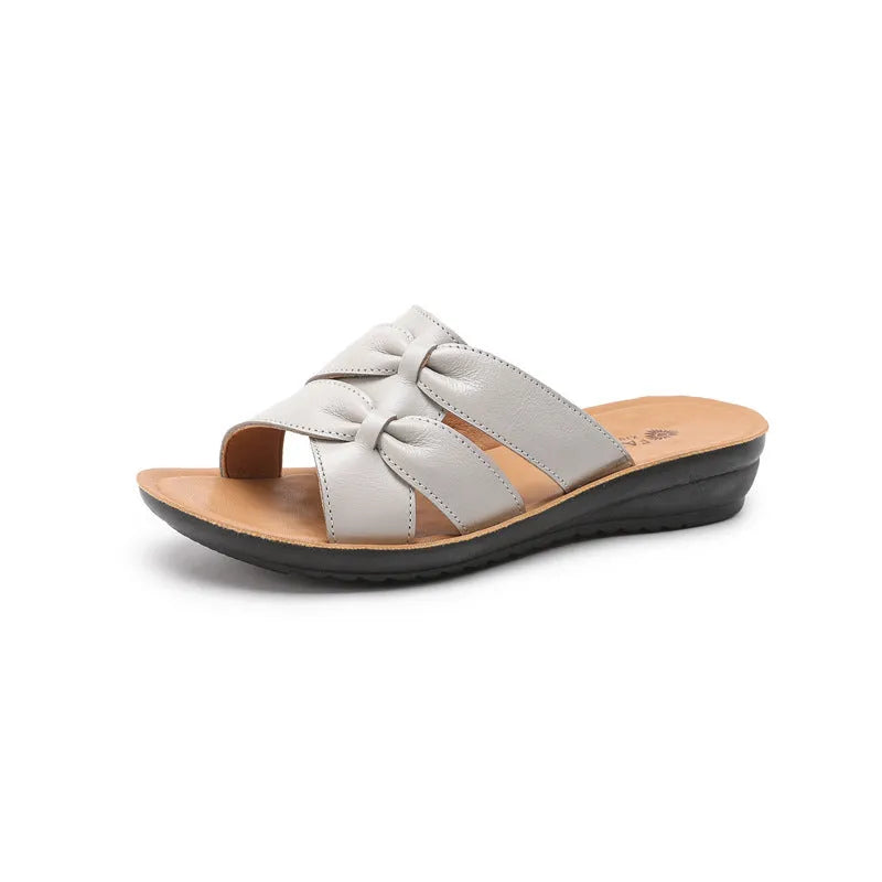 Women's beige cowhide slippers with a soft sole and synthetic leather lining, shown in a sandal style.