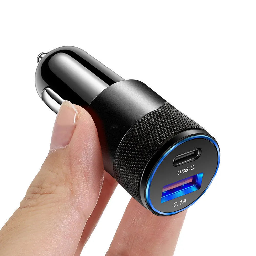 Aluminium alloy twin USB car charger shown in black, plugged into a car dashboard 12V socket.