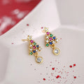 Gold Christmas stud earrings with diamond tree motif and water drop geometric shape on a light surface
