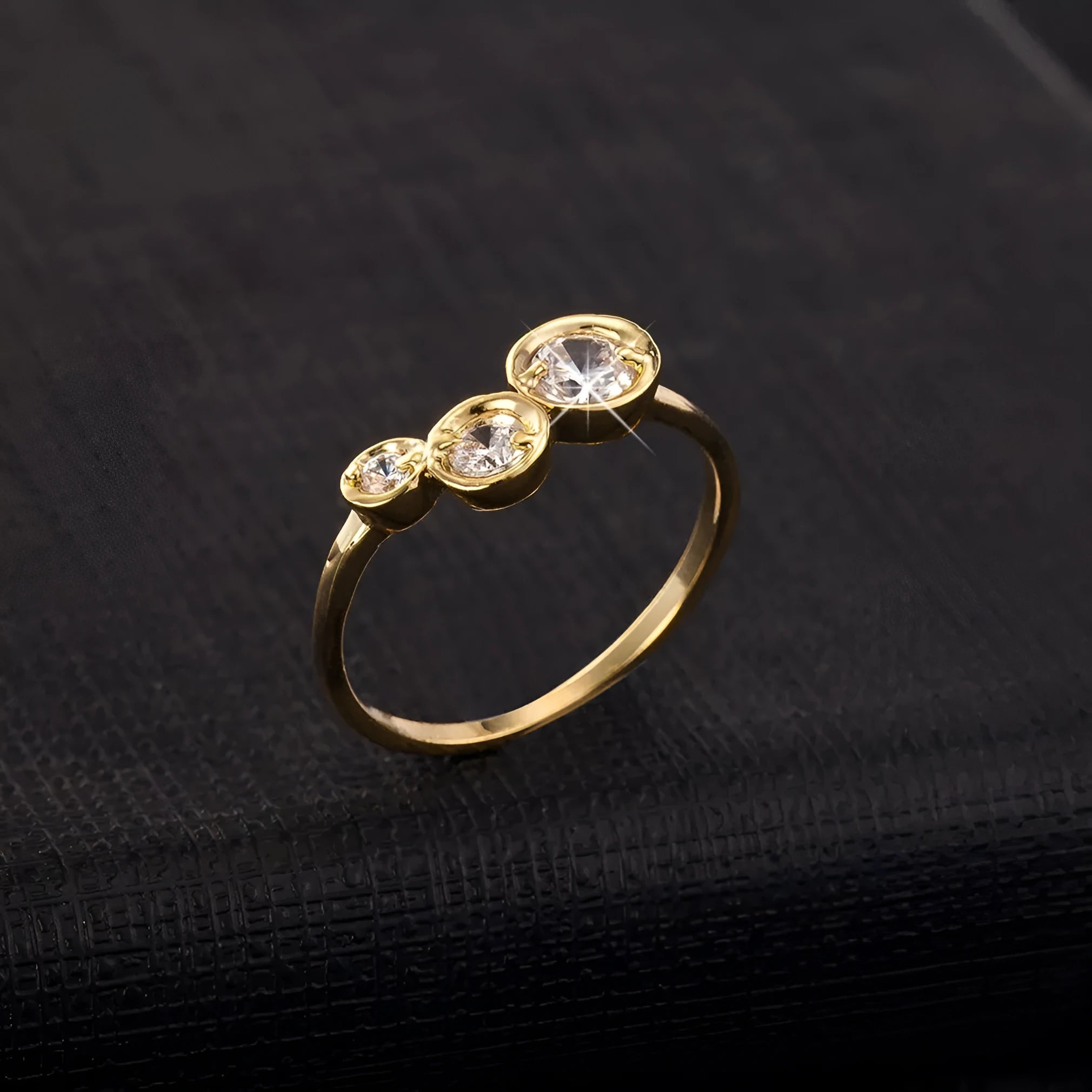 Three copper electroplated rings with lotus leaf design and round zircon stones in gold white zirconium tone on a flat surface