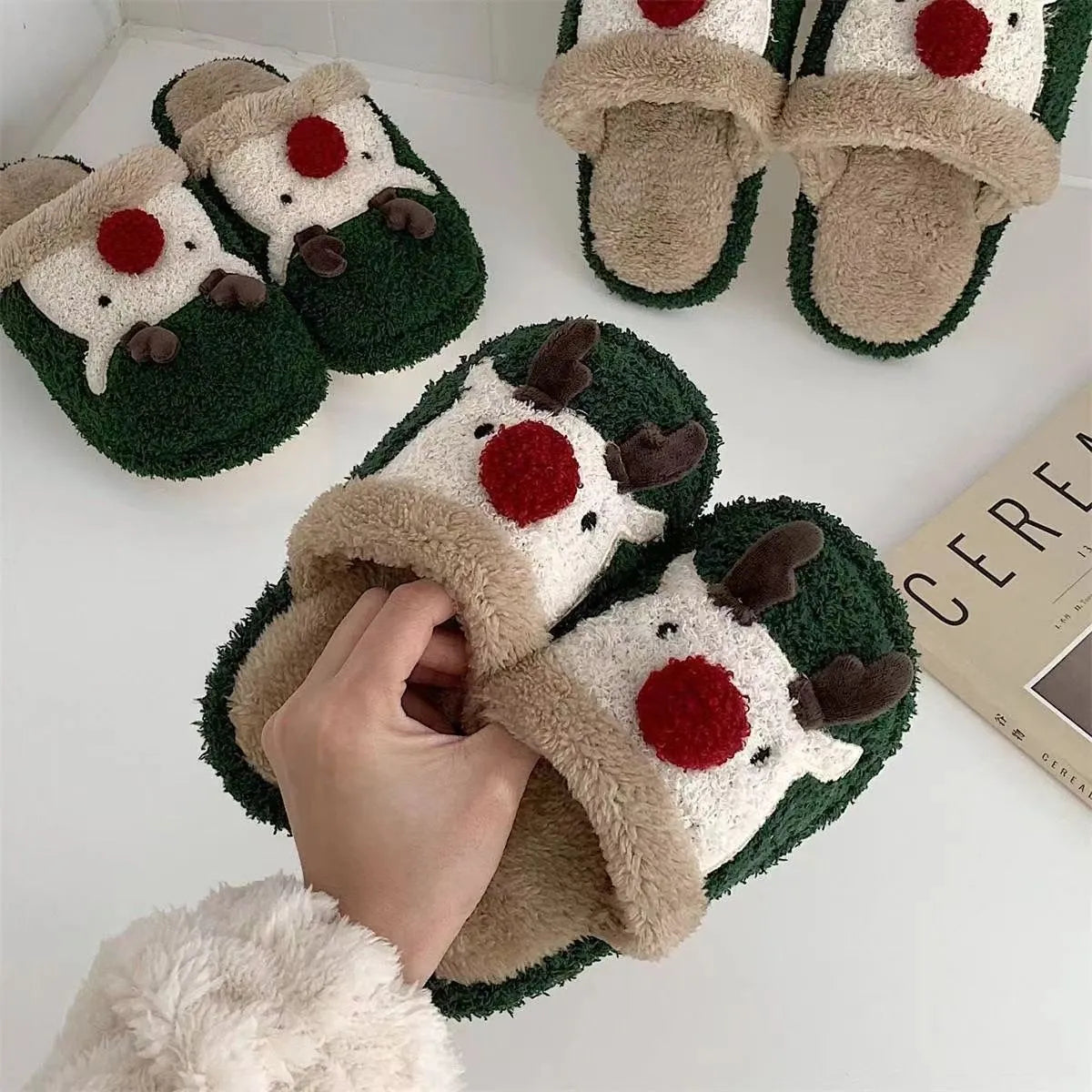 Women's brown Christmas elk plush slippers with non-slip PVC sole on a wooden floor.