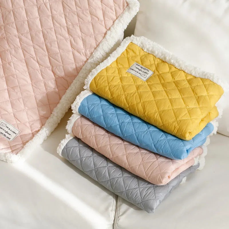 Blue quilted cloth pet blanket for cats lying flat, showing its rectangular shape and textured surface.
