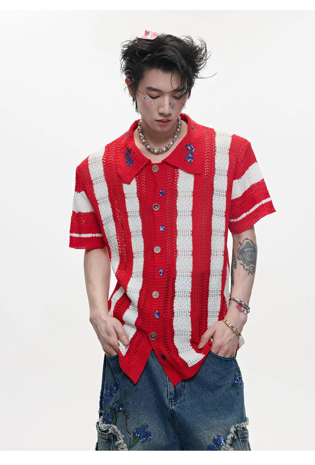 Man wearing a red and black patchwork striped knitted short sleeve shirt with a loose fit.