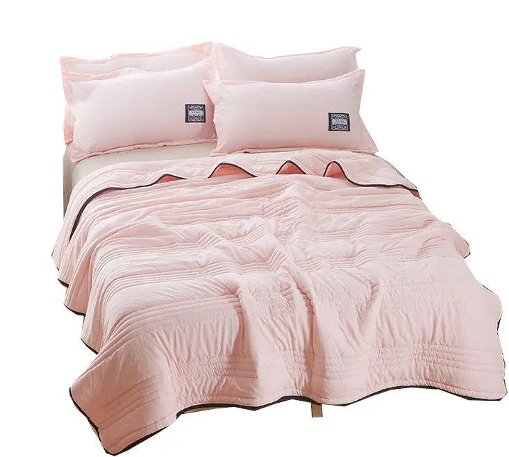 Plain colour seersucker summer cooling quilt shown in light pink on a bed.