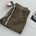 Man wearing beige loose straight-leg casual pants with a drawstring waistband.