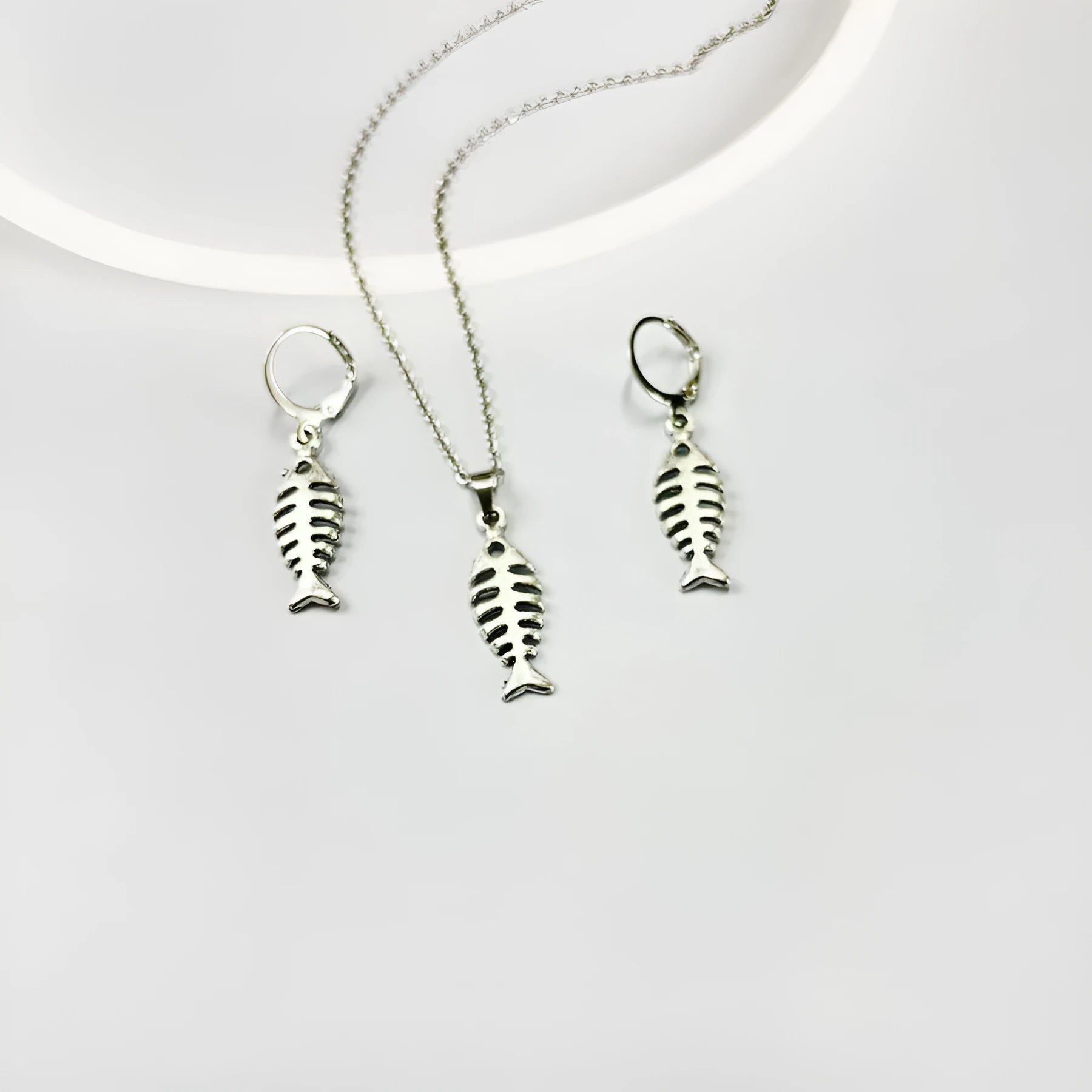 Women's fishbone pendant necklace and matching earrings set with adjustable chain on retro background