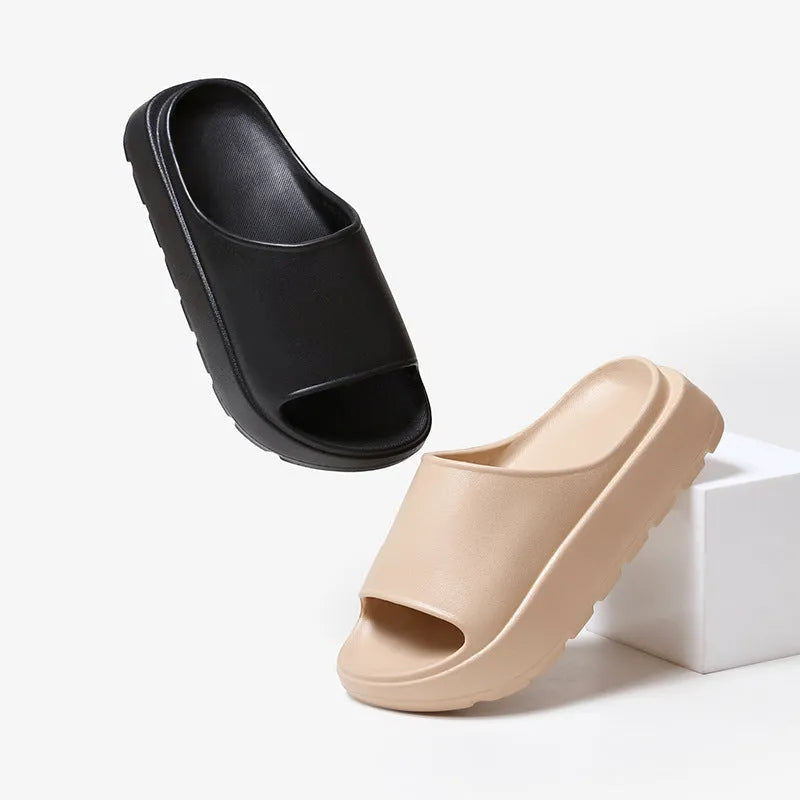 Women's beige open-toe beach slippers with a thick light-coloured sole on a wooden deck.
