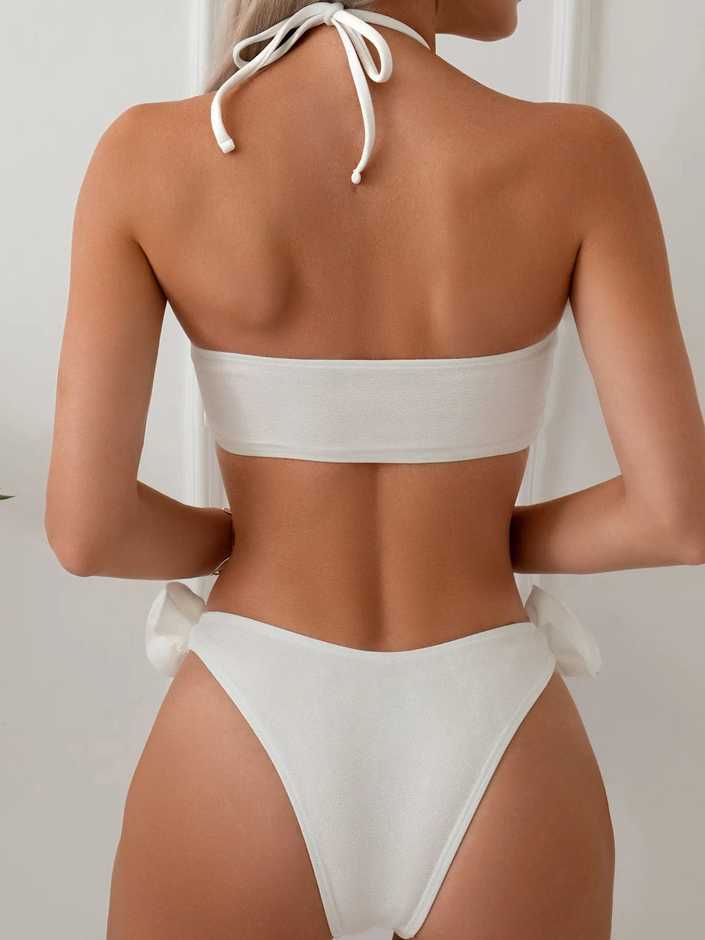 White halter neck lace-up swimsuit with three-dimensional floral details and brief bottom