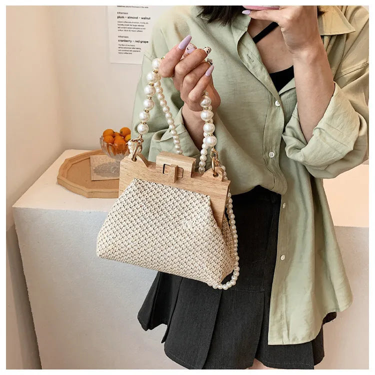 Women's woven straw shoulder bag with pearl chain detail showing horizontal square shape and internal compartments