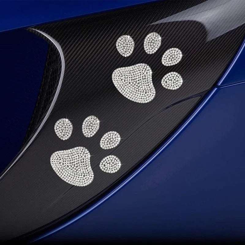 Close-up of a diamond-encrusted glass car sticker in butterfly and bear paw designs on a clear background.