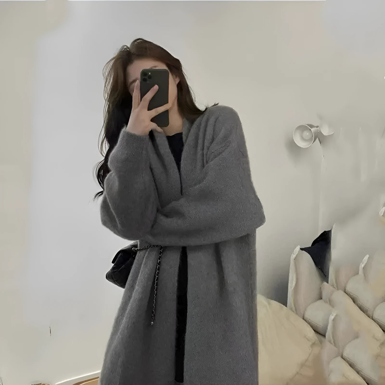 A woman wearing a loose, dark grey knitted chenille cardigan with a 3D-effect texture.