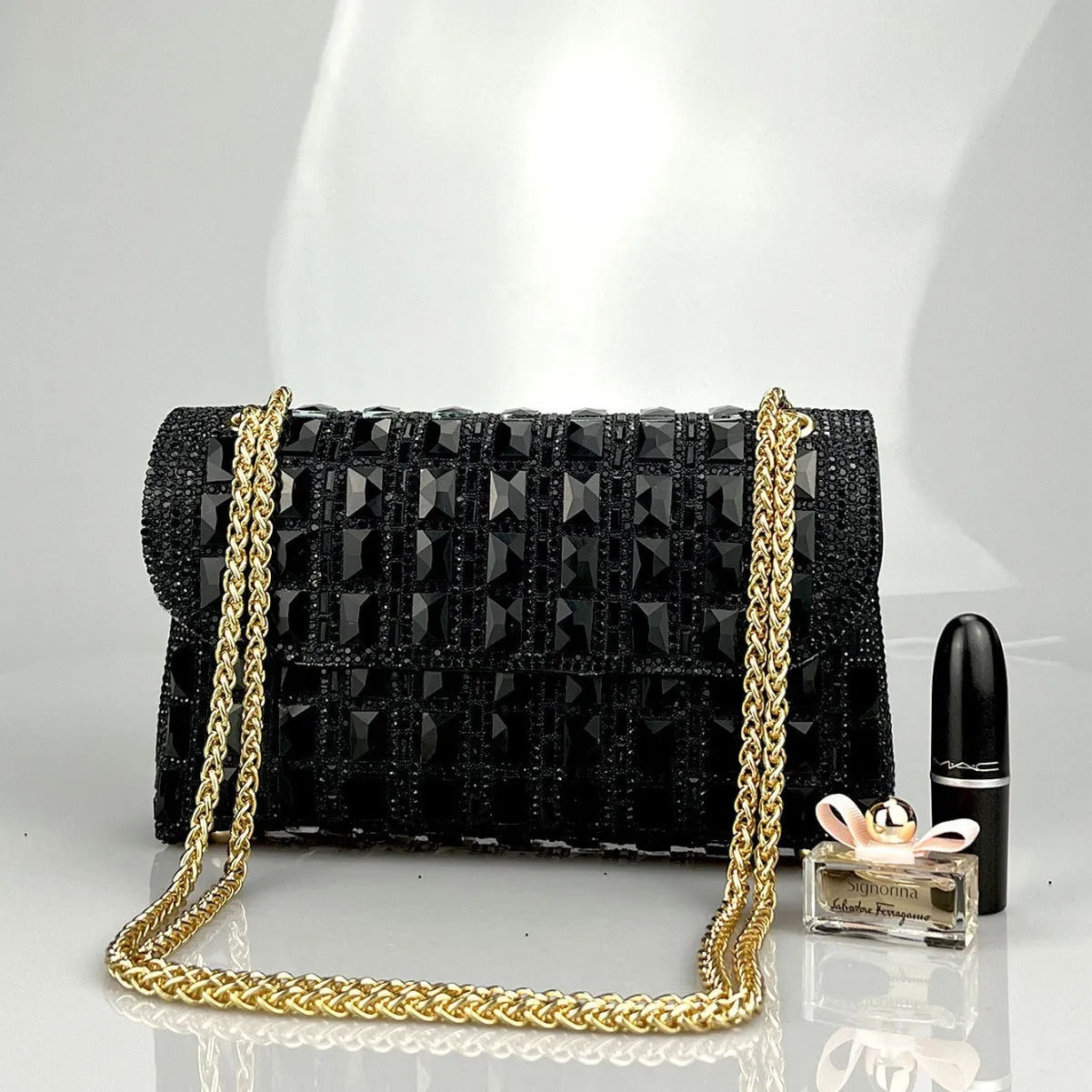 Silver rhinestone chain clutch bag with square shape and internal phone pocket on a table.