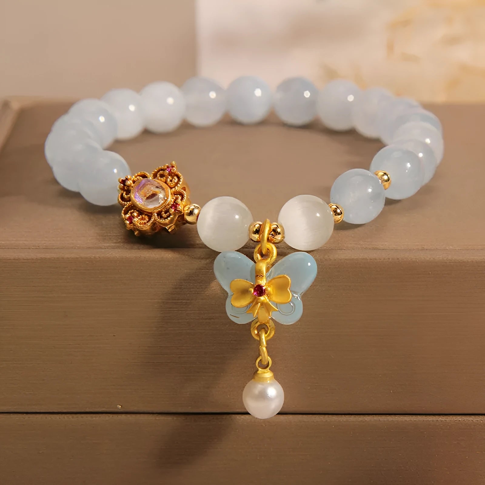 Aquamarine crystal butterfly pendant bracelet for women with rhinestone accents on a white background.