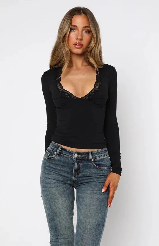 Women's slim-fit long sleeve black top with lace flower detail on front.