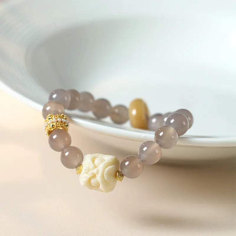 Hand-woven grey agate bracelet with 10mm round beads and mellite decorative accents.