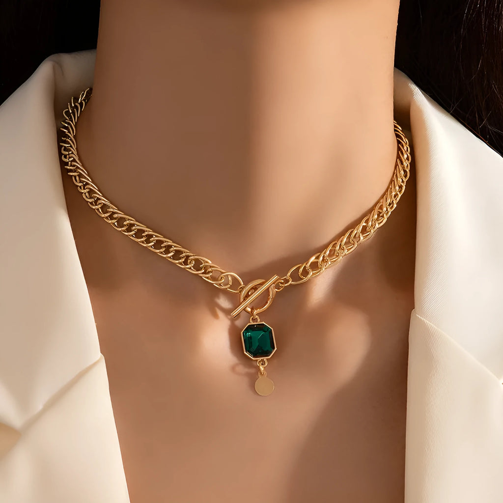 Gold titanium steel pendant necklace with geometric design and emerald zircon centre on Cuban link chain