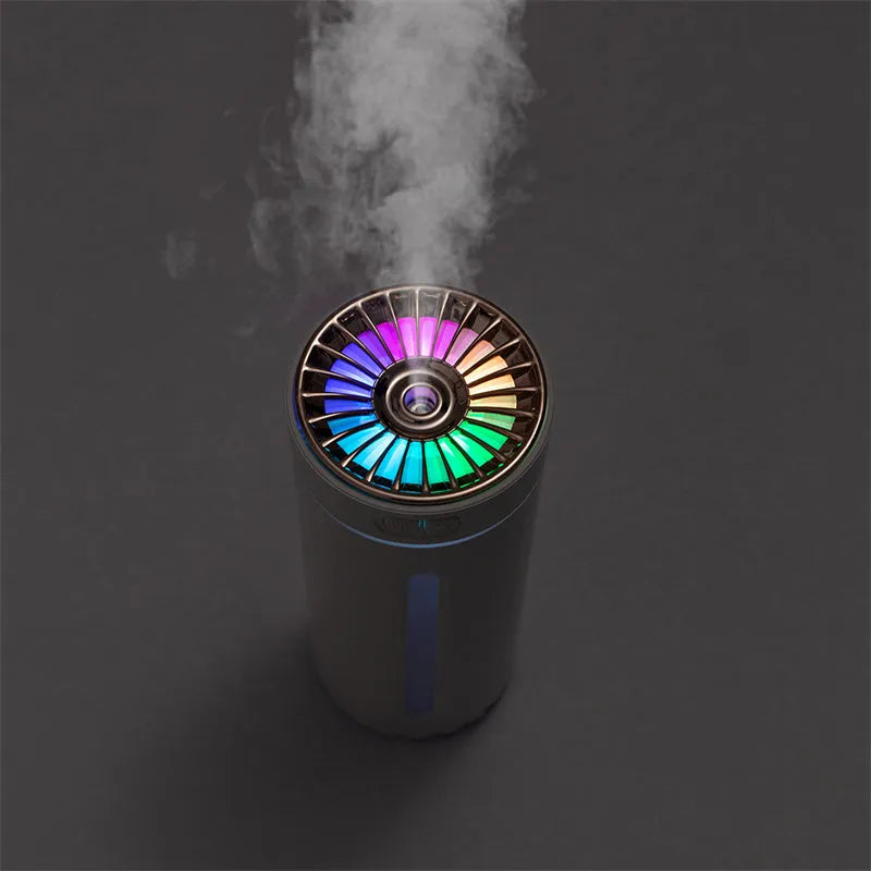 Black and white portable USB rechargeable car humidifier with colourful LED lights on a desk.