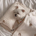 Simple bear print square dog bed set with pillow, mattress, and quilt on a floor.