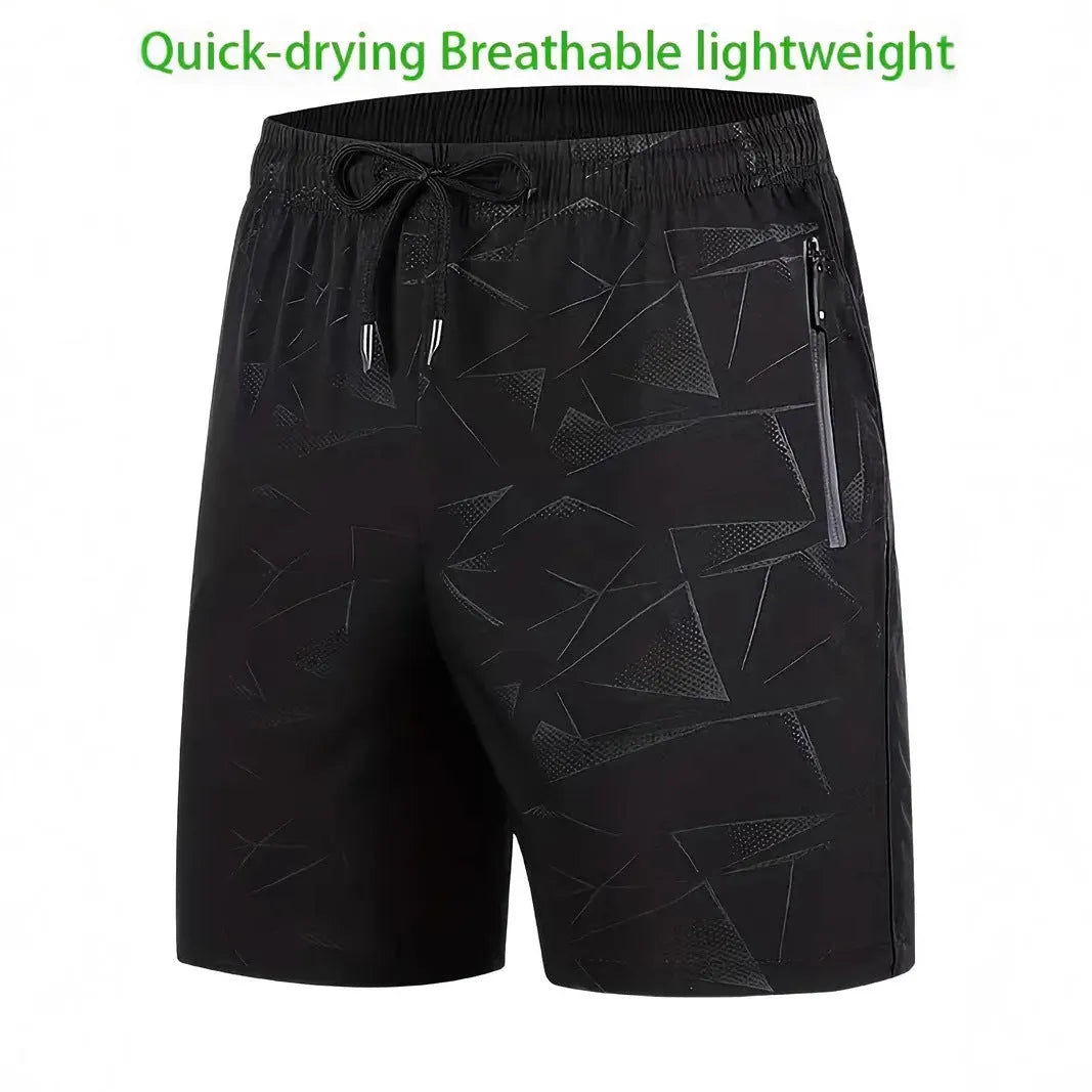 Man wearing loose grey printed polyester sports shorts on a beach.