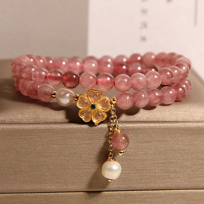Close-up of a women's bracelet with a strawberry quartz four-leaf clover charm on an alloy chain.