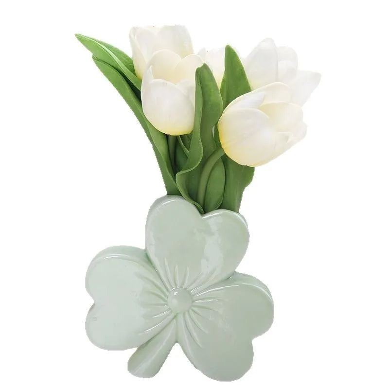 White porcelain clover-shaped ceramic vase on a desk, shown in light green colour.