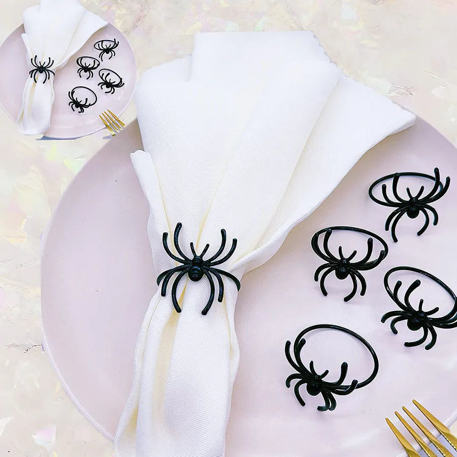 Set of six black metal spider-shaped napkin rings for Halloween table decorations.
